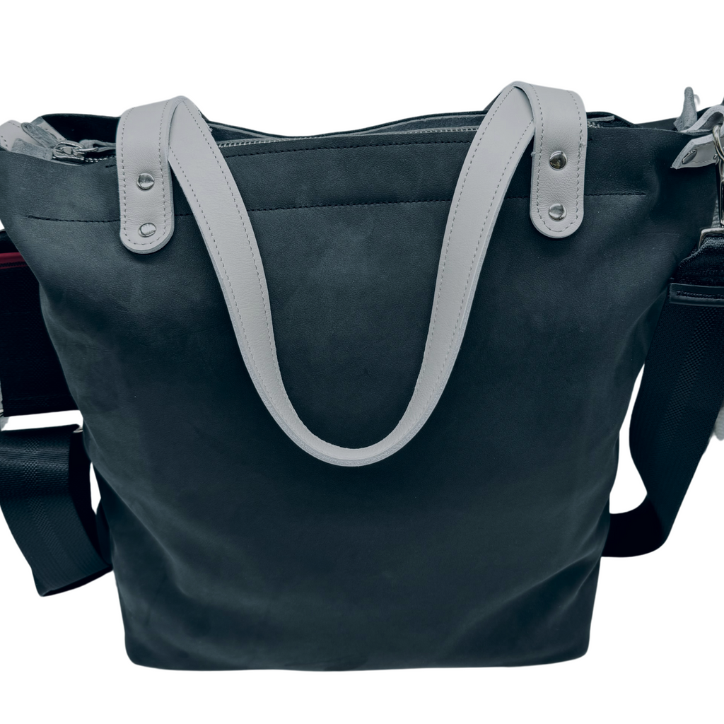 Onyx black leather bag and travel tote or work bag with a zipper and made sustainably by Pingree Detroit,
In Detroit, with upcycled leather, pictured here with the seat belt crossbody strap. Made for travel or weekender bag. 