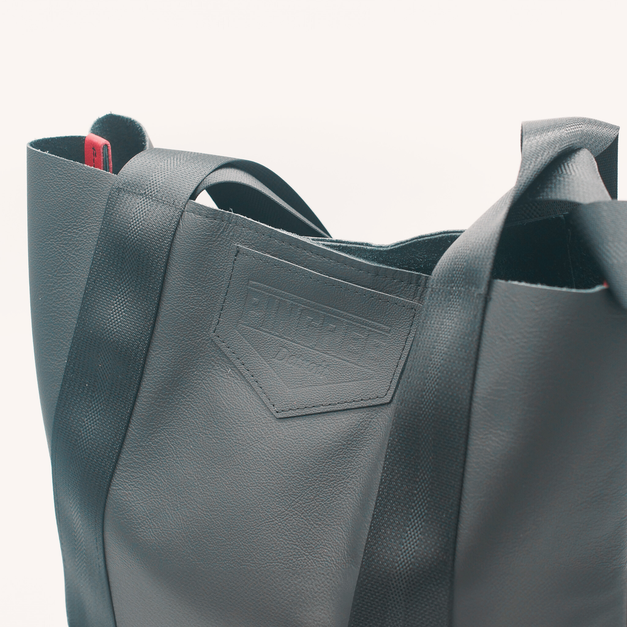 Detroit made leather bag with seatbelt handles, handmade in the USA, in Detroit, MI with upcycled leather from the automotive industry and handmade leather bag by Veterans and Detroiters. Pictured here in a black leather.