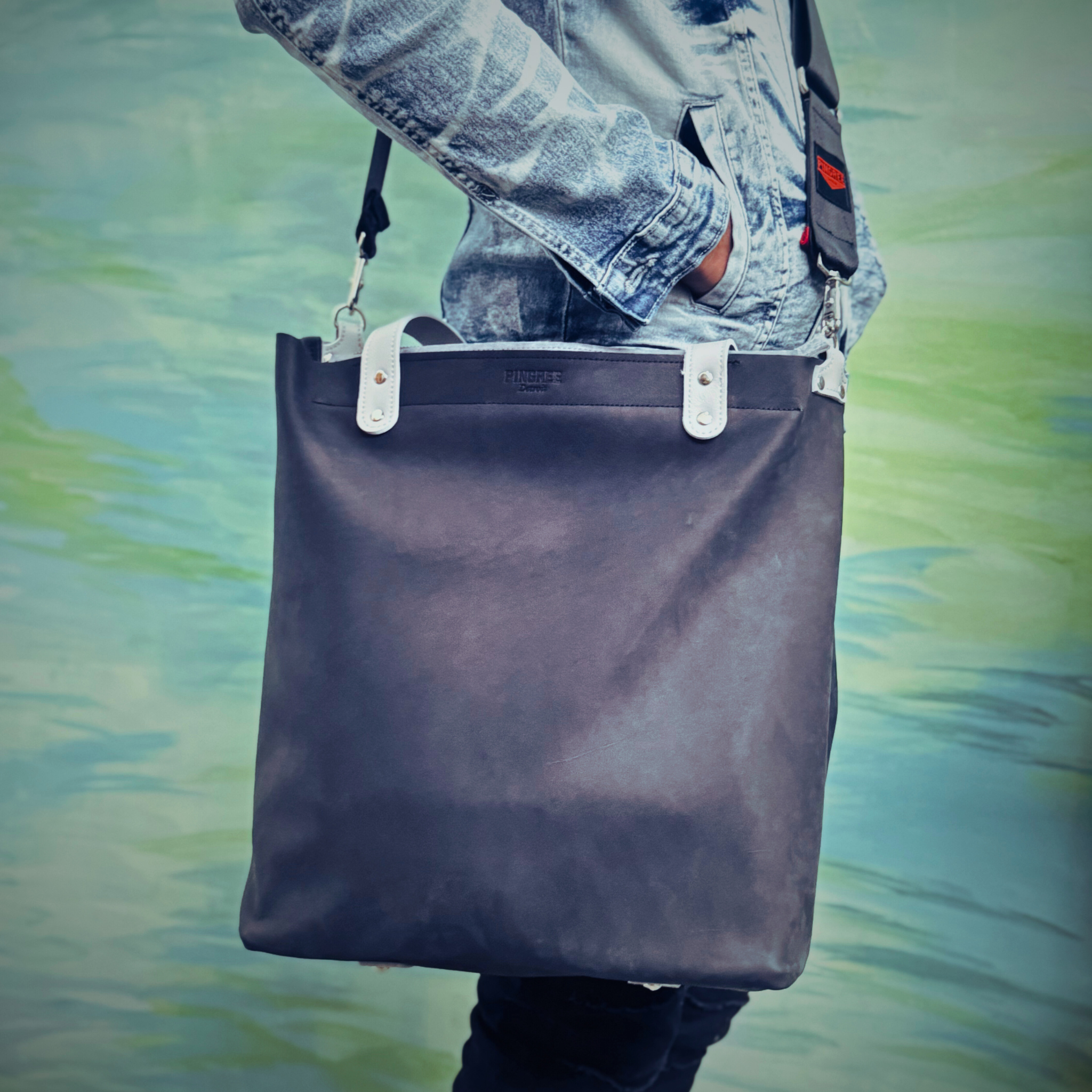 Onyx black leather bag and travel tote or work bag with a zipper and made sustainably by Pingree Detroit,
In Detroit, with upcycled leather, pictured here with the seat belt crossbody strap. Made for travel or weekender bag.