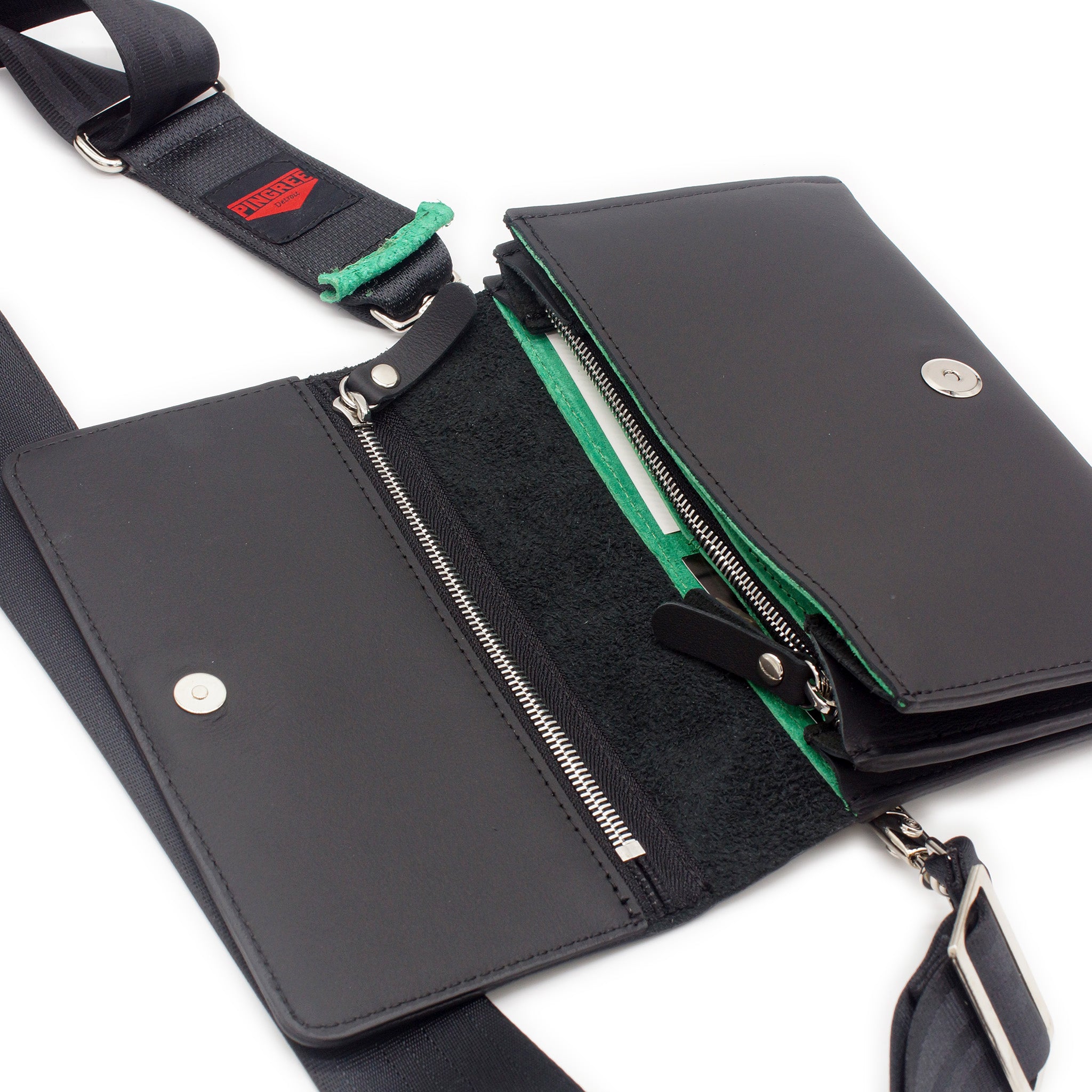 The Adeline Lux, pictured here open with seatbelt straps, a Shamrock Green interior, and exterior all black leather, upcycled from the automotive industry, with clean rounded corners, magnetic closure, and a wristlet. This 5-in-1 bag is handmade in Detroit, MI USA, with upcycled leather from the automotive industry. Each comes with a picture of the Veteran or Detroiter who made it.