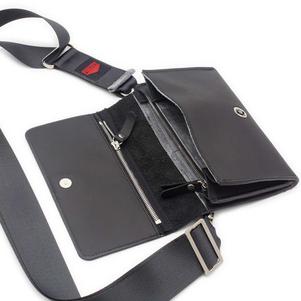 The Adeline Lux, pictured here open with seatbelt straps, a grey interior, and exterior all black leather, upcycled from the automotive industry, with clean rounded corners, magnetic closure, and a wristlet. This 5-in-1 bag is handmade in Detroit, MI USA, with upcycled leather from the automotive industry. Each comes with a picture of the Veteran or Detroiter who made it. 