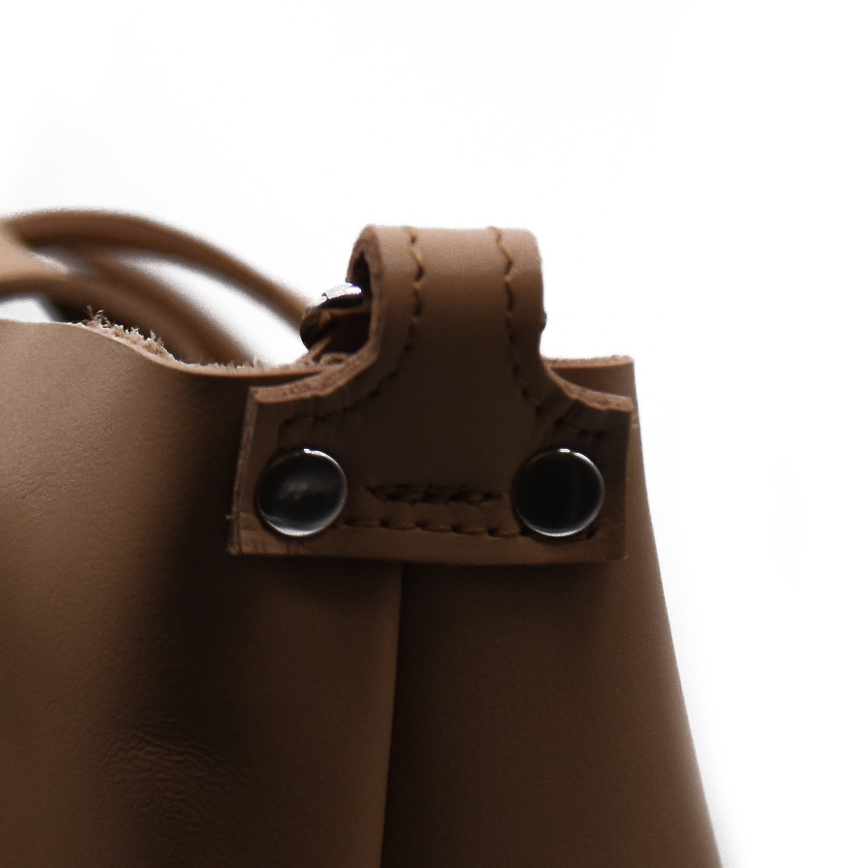 Close-up of a brown leather product with stitching details on a white background