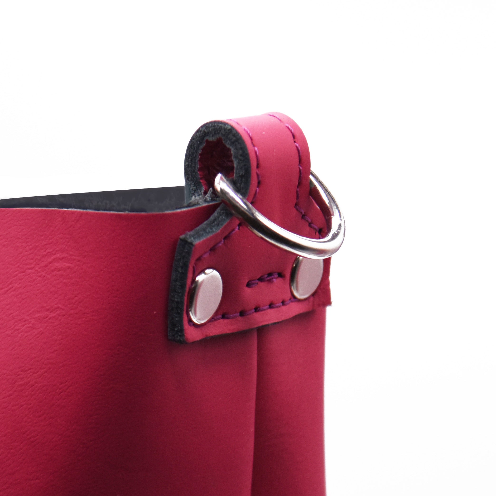Close-up of a red leather bag with a silver ring on a white background. Hot pink shopper tote bag with black accents on a white background. Made in Detroit. Leather bag crafted from upcycled automotive leather. Crossbody strap available. Bag made by Pingree Detroit. Perfect for wedding anniversaries and employee retreats and gifts. 