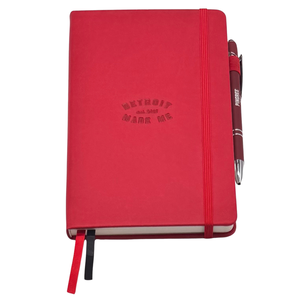Red notebook with 'Detroit Made Me' text and a pen on a white background. Our hand assembled Journal crafted with 100% recycled paper pulp with lined pages. Detroit made me. Includes a pen, double bookmarks a front pocket and a rear pocket and elastic closure that we sew for reinforcement. A 5 size, comparable to a moleskine style, fits inside of our portfolio or works great as a standalone.
