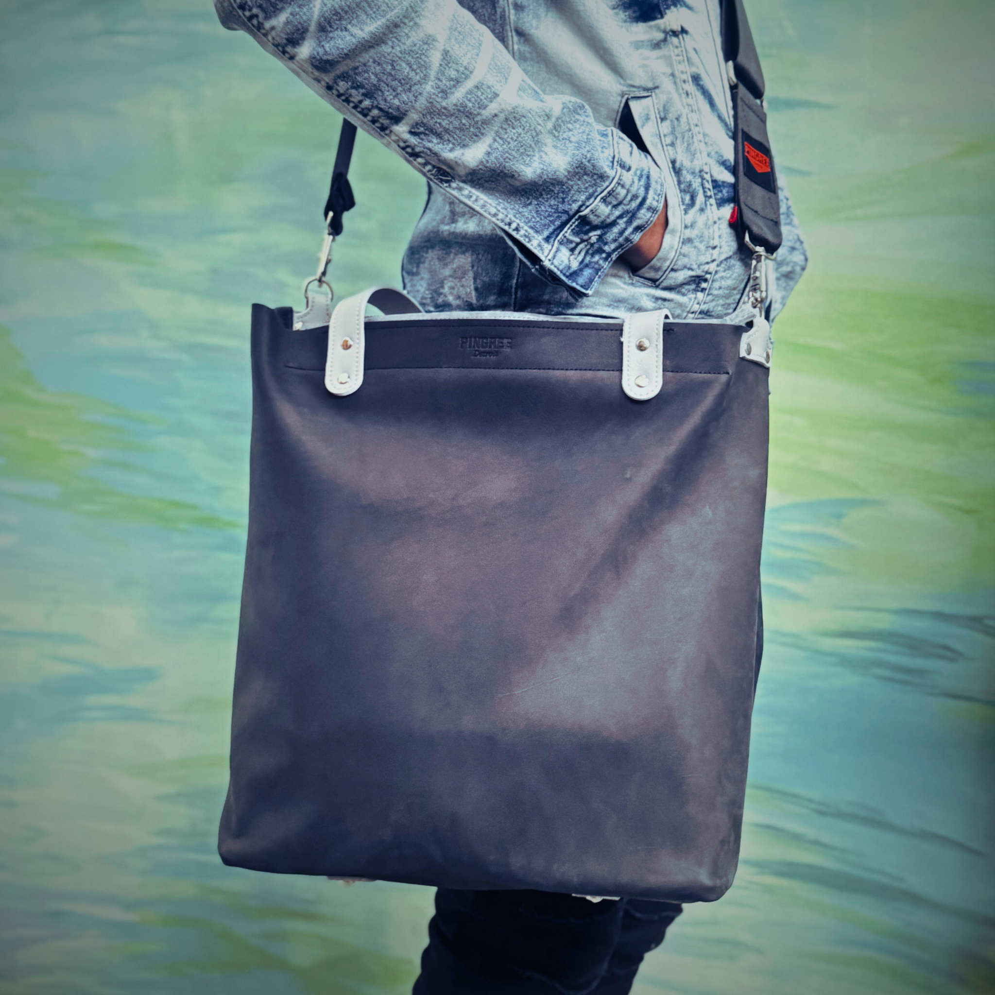 Onyx black leather bag and travel tote or work bag with a zipper and made sustainably by Pingree Detroit,
In Detroit, with upcycled leather, pictured here with the seat belt crossbody strap. Made for travel or weekender bag. 