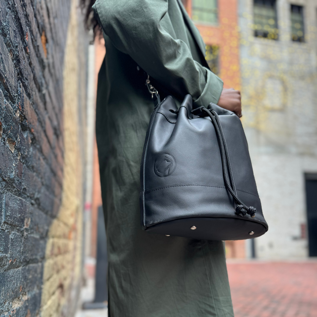 drawstring bucket bag handmade in detroit pictured here in black with the sustainable cording showing, on a Detroit maodel, with leather made from upcycled cars