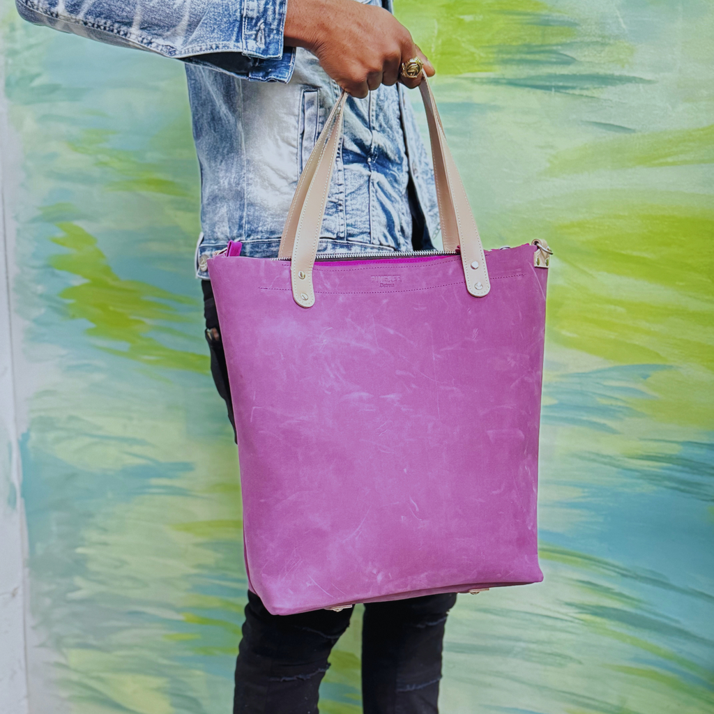 Purple leather bag and travel tote or work bag with a zipper and made sustainably by Pingree Detroit,
In Detroit, with upcycled leather, pictured here held up to show the tote features without the seat belt crossbody strap