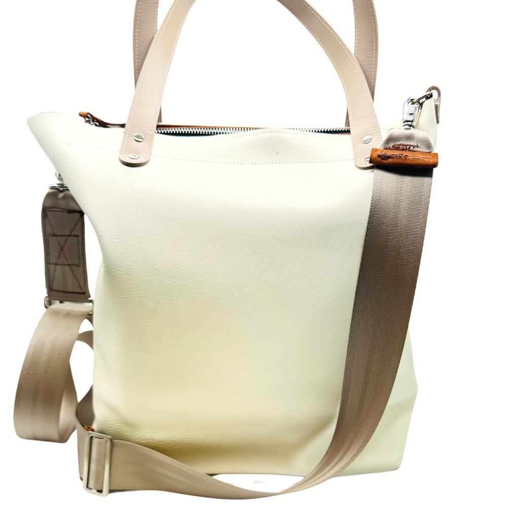 Cappuccino color leather bag and travel tote or work bag with a zipper and made sustainably by Pingree Detroit,
In Detroit, with upcycled leather, pictured here with the adjustable seat belt crossbody strap. Made for travel or weekender bag. Carry-on compliant. 
