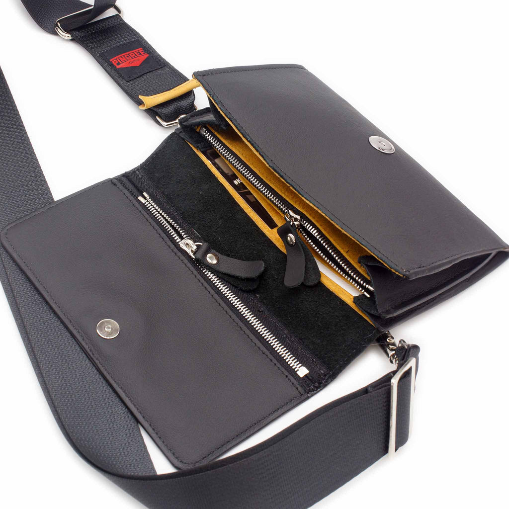 The Adeline Lux, pictured here in the front profile, open showing the marigold interior, and seatbelt straps, with all black leather, upcycled from the automotive industry, with clean rounded corners, magnetic closure, and a wristlet. This 5-in-1 bag is handmade in Detroit, MI USA, with upcycled leather from the automotive industry. Each comes with a picture of the Veteran or Detroiter who made it. 