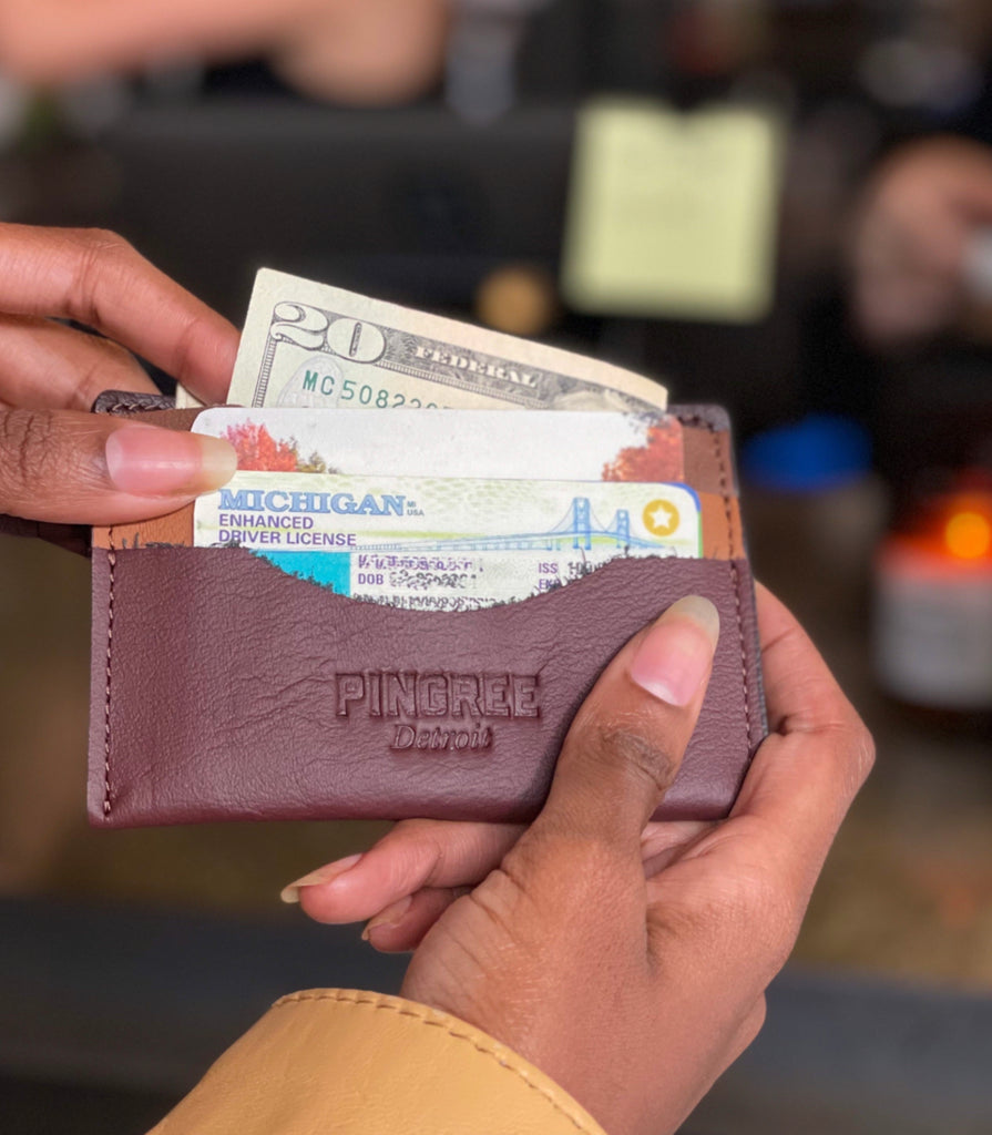 Whittier Wallet filled with cash and cards at checkout counter. Made in Detroit Michigan from upcycled automotive leather.